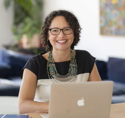 A portrait of Rebecca Bennett sitting at a desk with a laptop