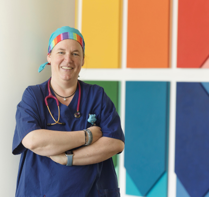 A portrait of Britta Regli-von Ungern-Sternberg standing in front of a rainbow mural