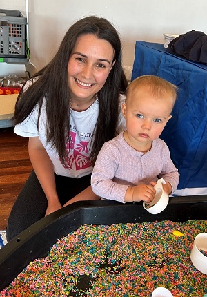 Photo of an smiling adult woman beside a young toddler