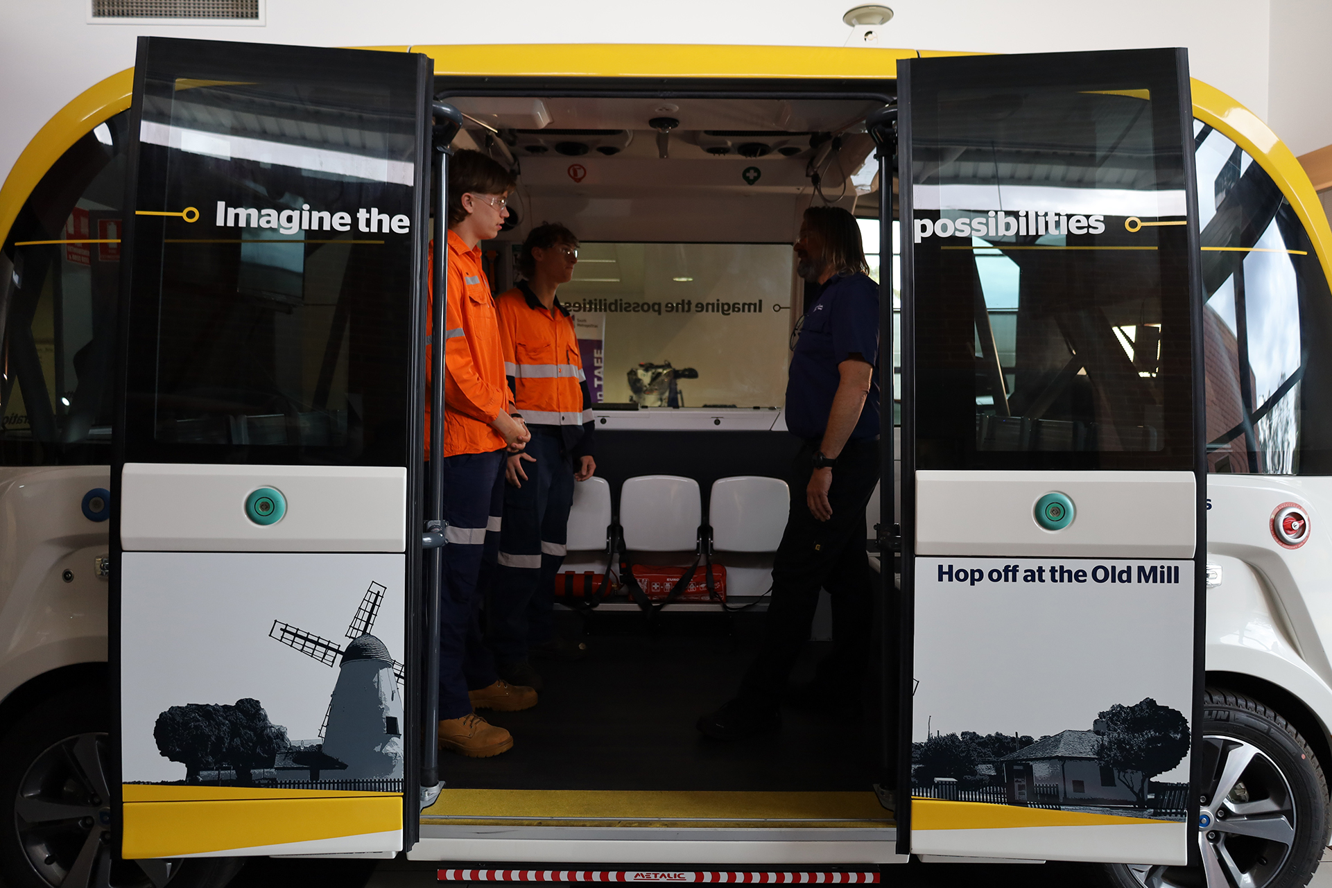 Two apprentices standing inside the RAC Intellibus with their lecturer 