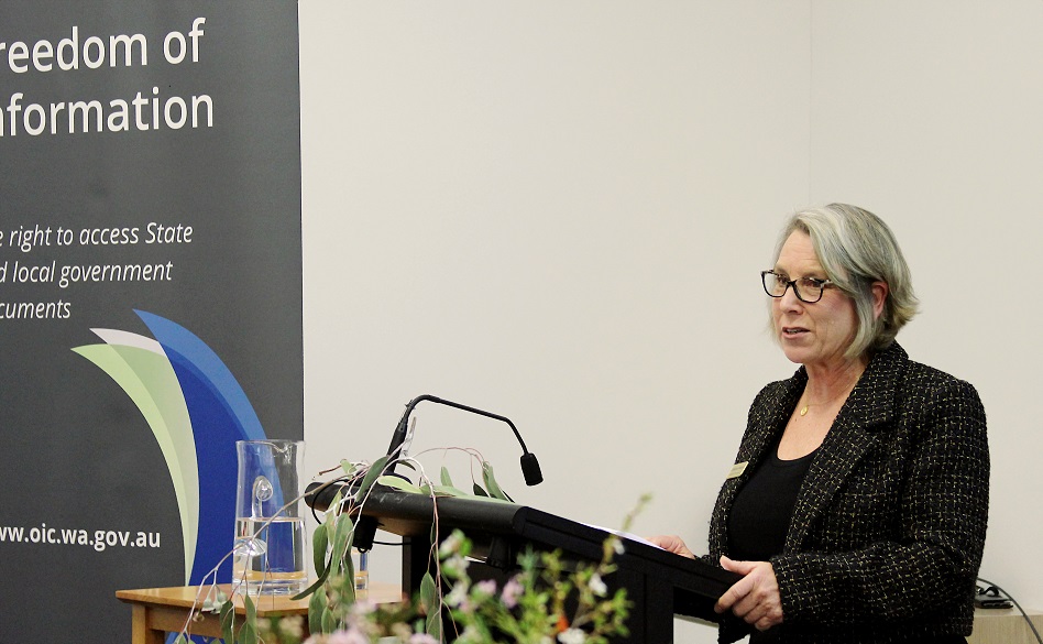 Suited woman standing in front of a lectern with a microphone