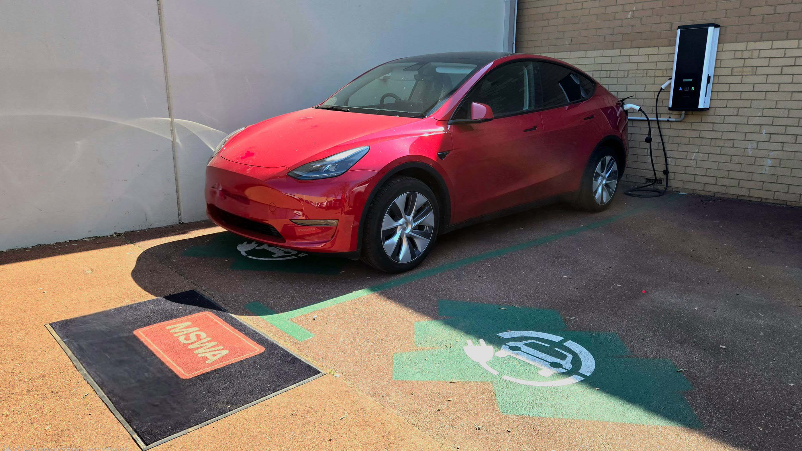 Red car in parking space next to an EV charger at MSWA