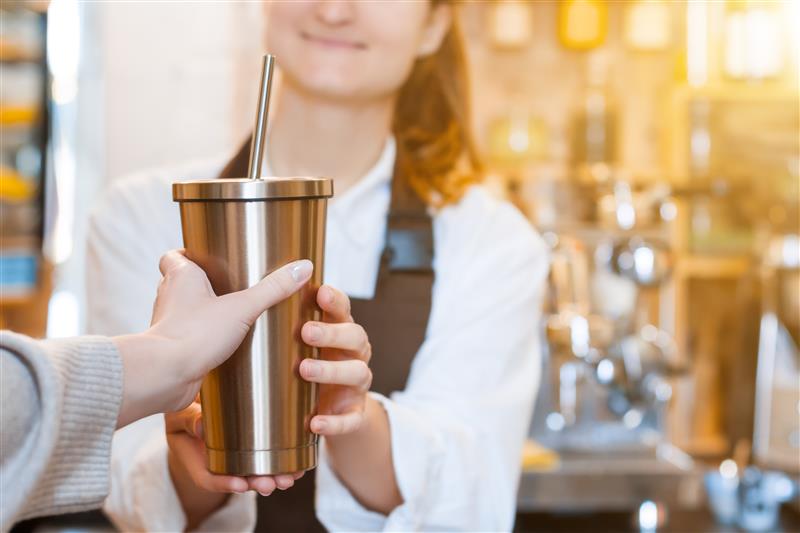 A young woman holding a reusable cold cup and straw