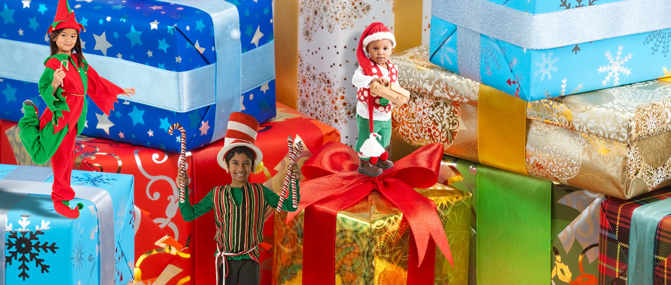 Dozens of Christmas presents wrapped up and smiling children dressed as elves