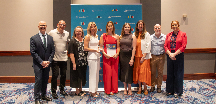 group photo of 9 adult people on stage at an event