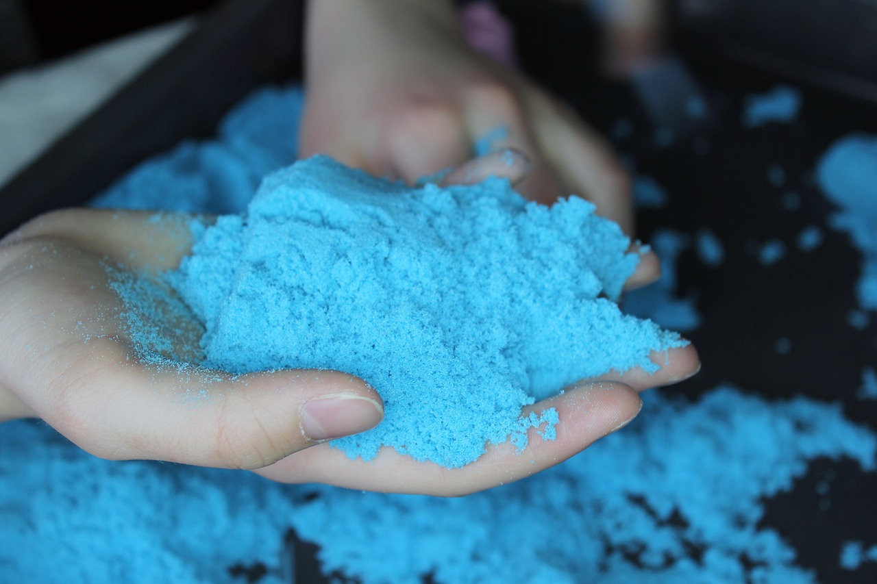 a hand holding coloured blue kinetic sand