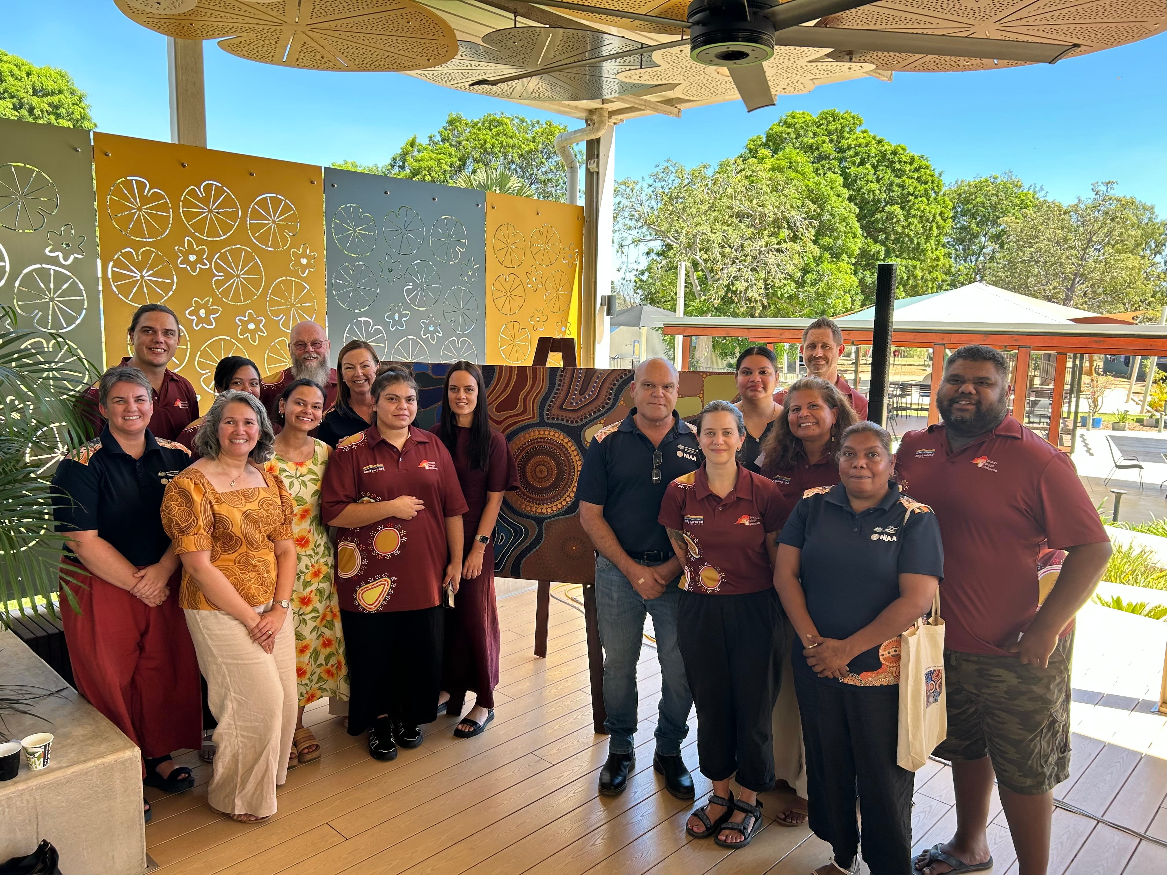 Group of people standing in front of an Aboriginal artwork