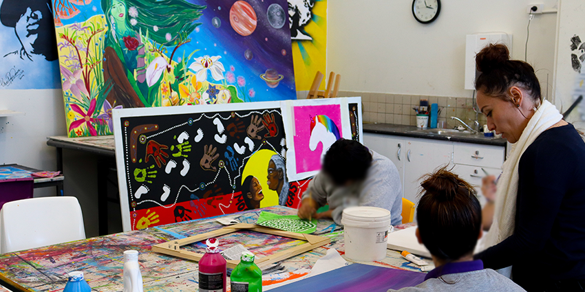 a group of students are learning form their art teacher