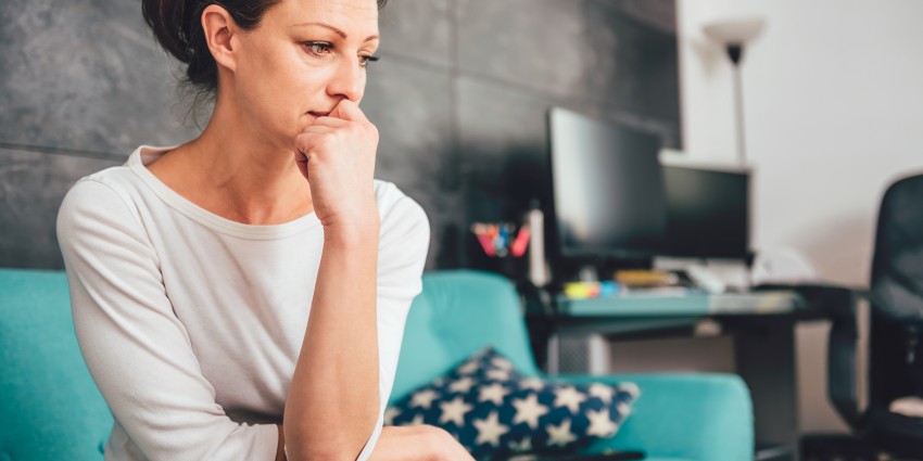 Woman sitting on a couch, looking concerned or lost in thought