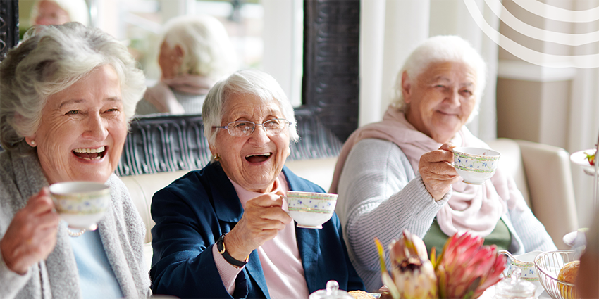Several senior women holding teacups and smiling.