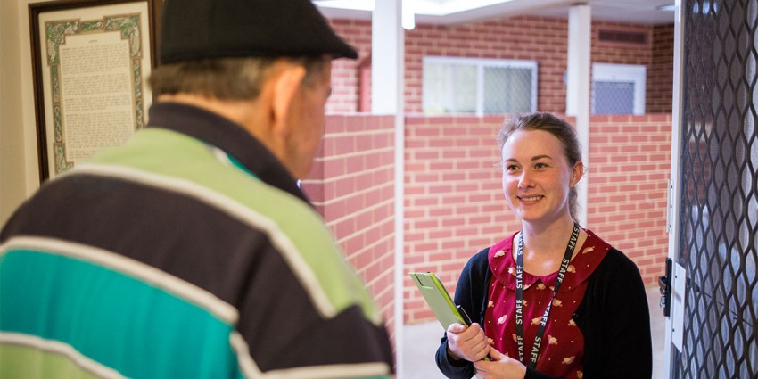 A volunteer at the front door of an elderly person.