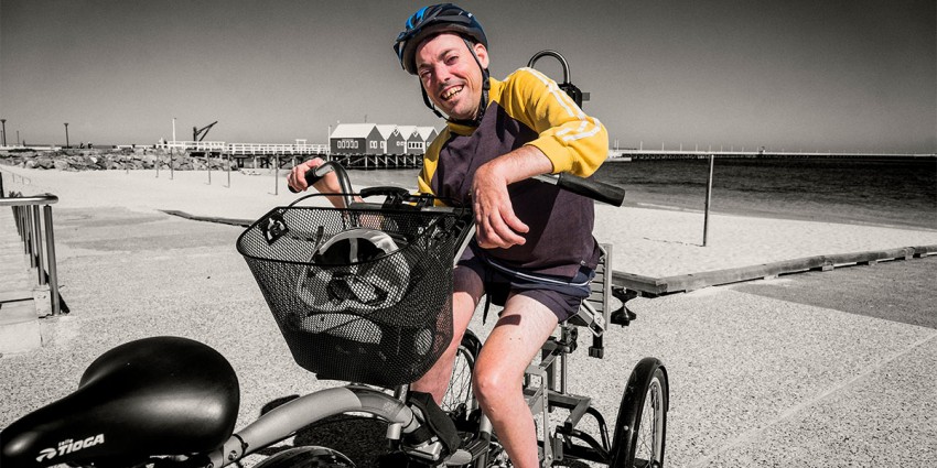 A smiling man in a wheelchair on the beach.