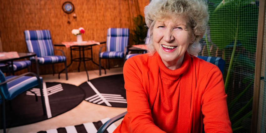An elderly housing tenant in her home, smiling.