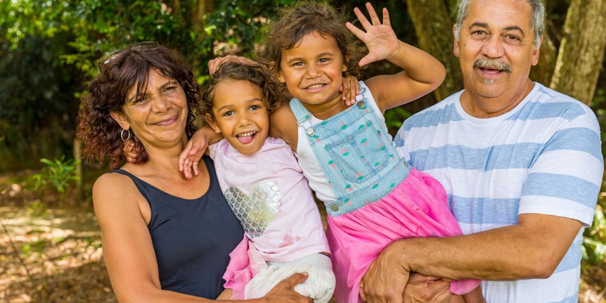 Grandparents holding their two grandchildren, smiling.