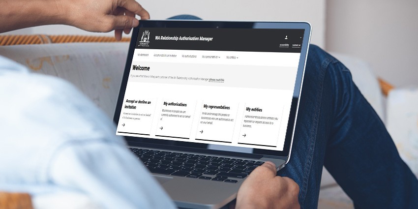 Man sitting with laptop on his lap looking at WA Relationship Authorisation Manager platform