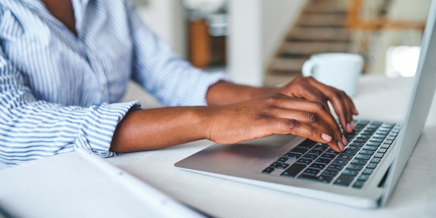 A close up image of a woman typing on a laptop keyboard.