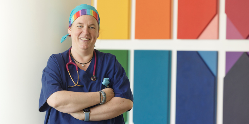 Portrait of Brita in front of a rainbow mural