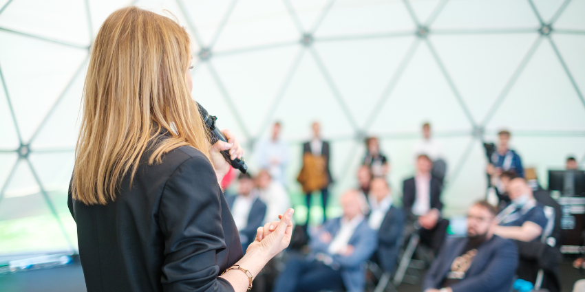 Back perspective of a female presenter talking to an audience