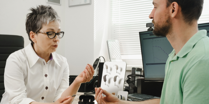 Patient visiting an ear specialist clinic. The two individuals are looking at hearing aids