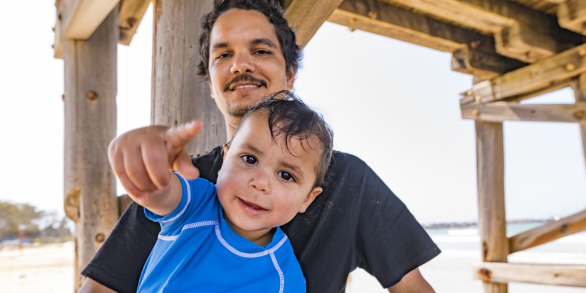 photo of a young aboriginal man holding a young child in his arms 