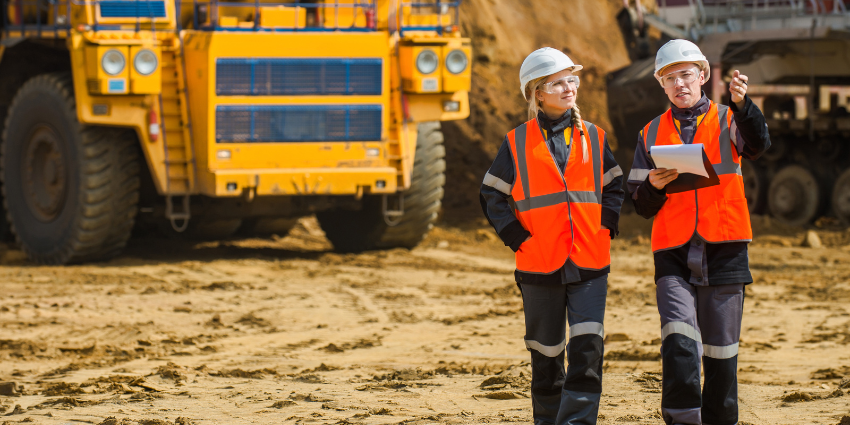 Pilbara mine site with 2 workers in front a mining truck