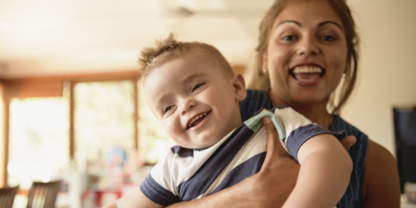 Portrait Of Woman Holding Young Son And Smiling Towards Camera 
