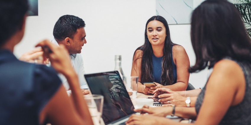 Image of four people around a desk with computers and collaborating