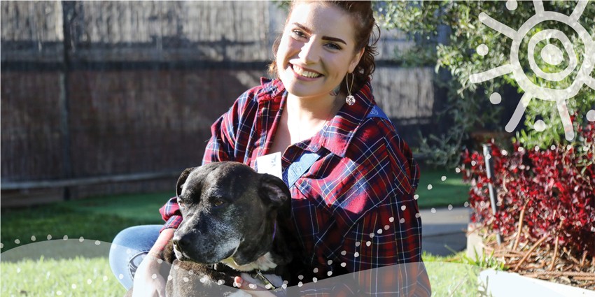 photo of a young woman in a garden holding a pet dog