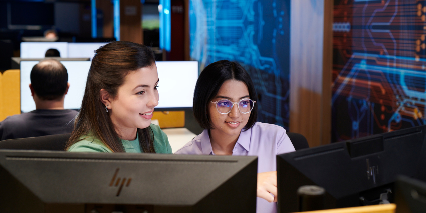 Two girls looking at computer monitor smiling