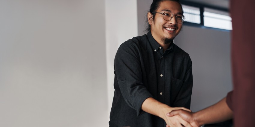 Image of a young Asian man shaking hands with someone