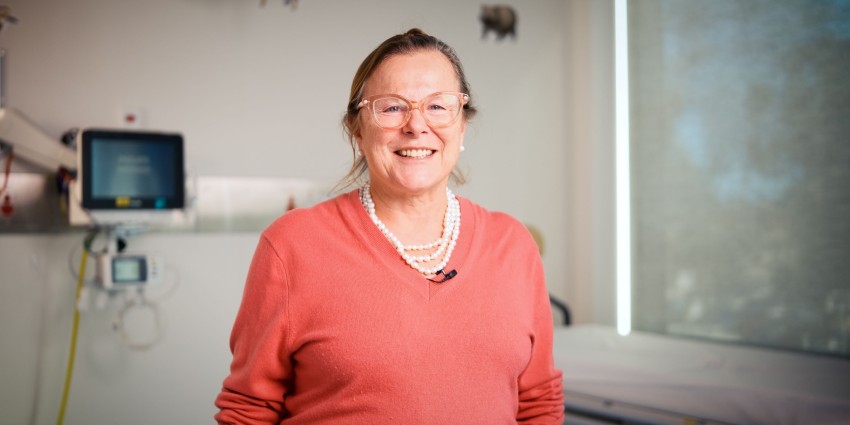 a smiling Fiona Wood wearing a peach jumper and a layered pearl necklace