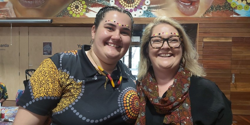 two ladies with black, red and yellow face paint smiling
