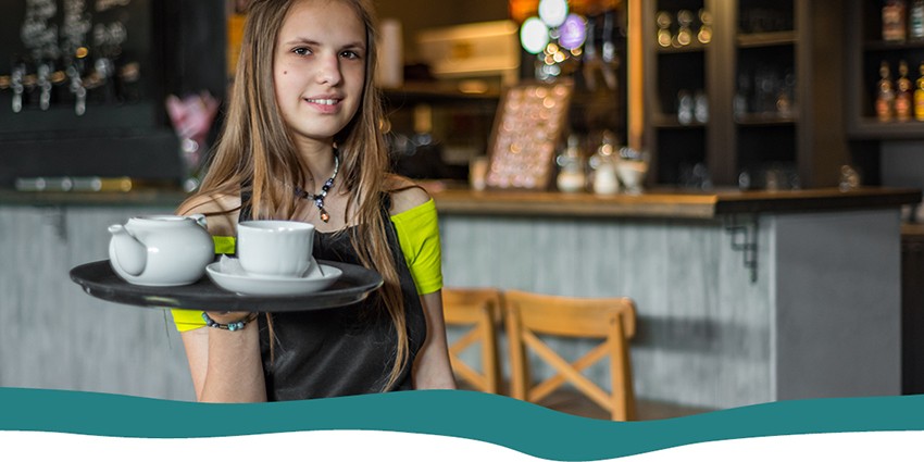 A teenager holding a tray of tea in a cafe