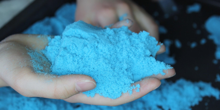 a hand holding coloured blue kinetic sand