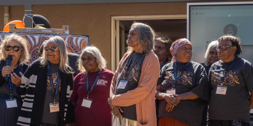 a group of Aboriginal women in an outdoor setting, watching an opening event