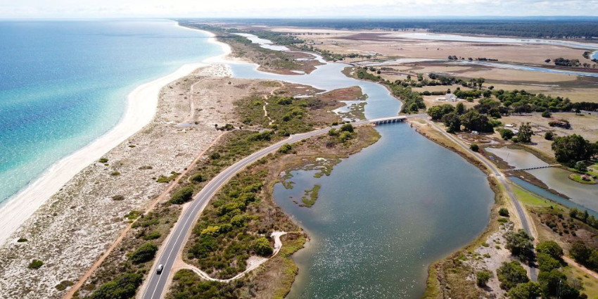 Aerial view of a coastal wetland with winding waterways, sandy shoreline and surrounding vegetation.
